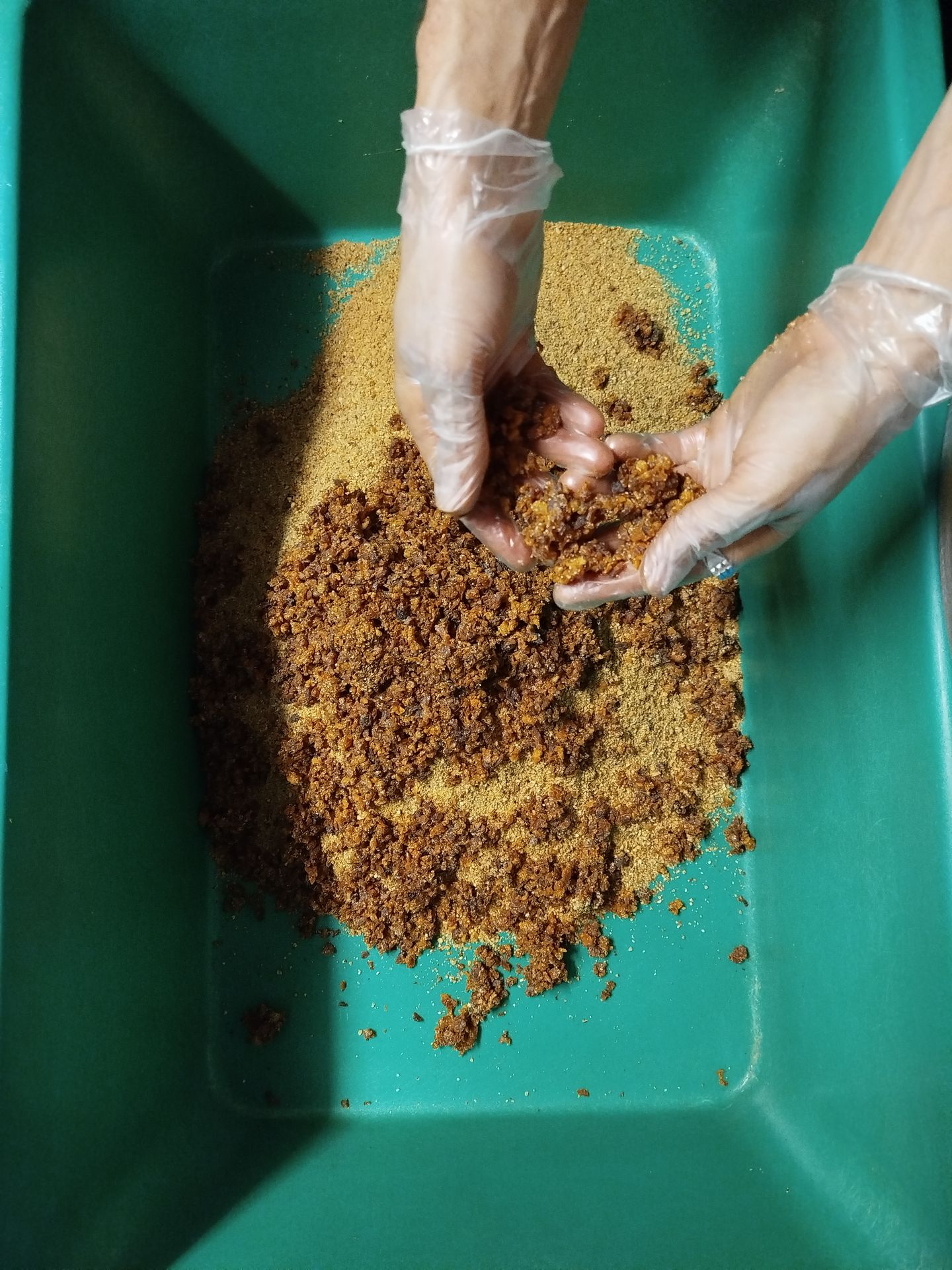 Mains gantées mélangeant la pâte des barres dans l'atelier de Malans